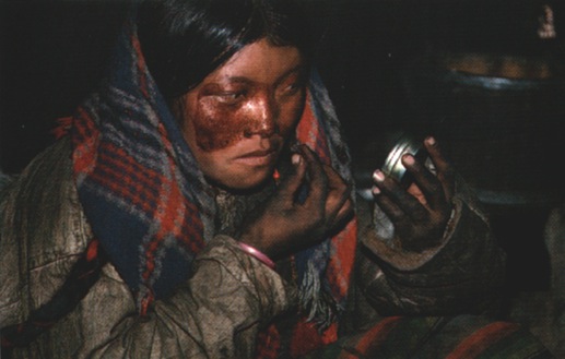 Nomad woman applying red face makeup